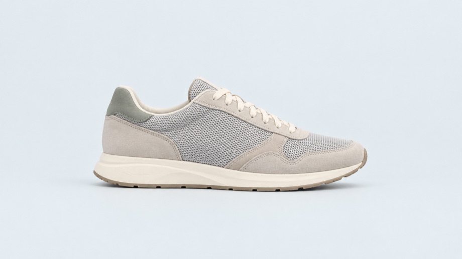 Grey running shoe on a pale blue studio background